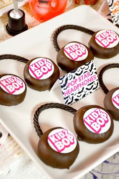 chocolate covered donuts with stickers on them sitting on a white plate next to other items