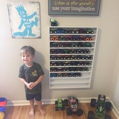 a young boy standing in front of a display of toy cars and toys on the floor