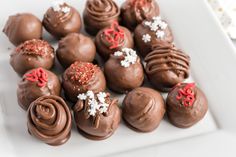 chocolate truffles with frosting and sprinkles on a white plate