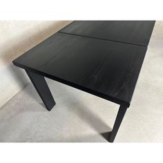 a black wooden table sitting on top of a white tile floor next to a wall