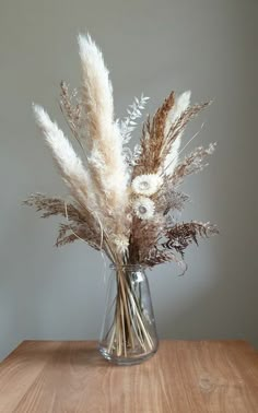 a vase filled with dried flowers on top of a wooden table