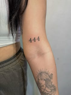 a woman's arm with a tattoo on it that reads 444 and has a sun above her head