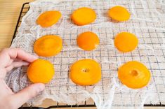 someone is placing oranges on a wire rack