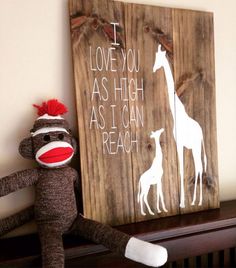 a sock monkey sitting next to a wooden sign that says i love you as high as i can reach