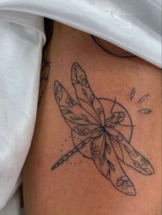 a woman's thigh with a dragonfly tattoo on it