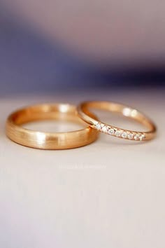 two gold wedding rings sitting on top of each other