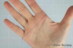 a person's hand with two needles sticking out of it