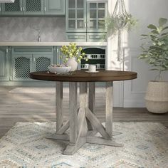 a round table in the middle of a room with blue cabinets and rugs on the floor