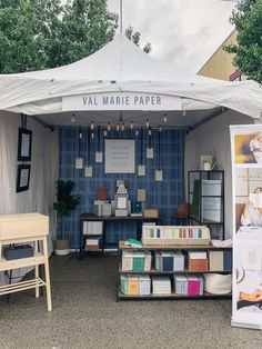 a tent that has some books on it in front of a table with chairs and other items