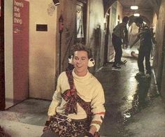 a young man sitting on the ground with headphones in his ears and another person standing behind him