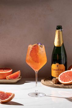 grapefruit, orange juice and champagne are on the table next to some sliced grapefruits