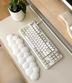 a computer keyboard sitting on top of a desk next to a plant and mouse pad