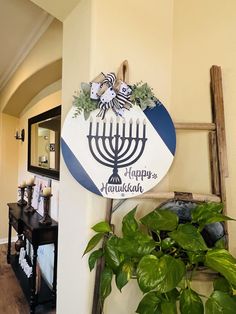 a hanukkah menorah sign hangs on the wall next to a potted plant