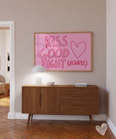 a pink sign that says kiss good night on the wall next to a wooden cabinet