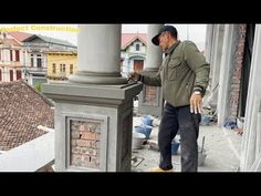 a man standing on top of a roof next to a tall pillar with a hammer in it