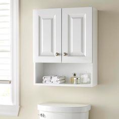 a white cabinet above a toilet in a bathroom