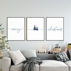 three christmas cards hanging on the wall above a couch in a living room with a christmas tree