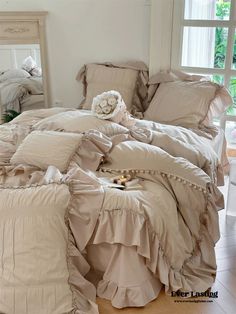 an unmade bed with ruffles and pillows on it in a bedroom next to a window