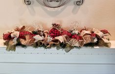 a fireplace mantel decorated for christmas with red and white plaid bows, pine cones and evergreens