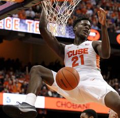 the basketball player is jumping up to dunk the ball in front of his opponent