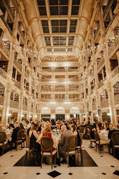 people sitting at tables in the middle of a large room with many bookshelves