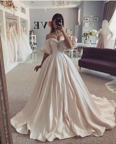 a woman in a wedding dress taking a selfie with her cell phone while standing in front of a mirror