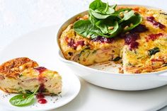 a casserole with spinach and cheese on a white plate next to a piece of bread