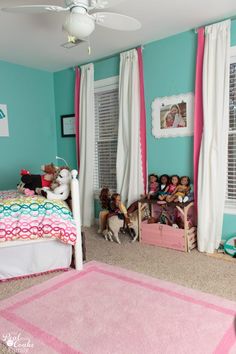 a bedroom with blue walls and pink carpeted flooring, two children's toys on the bed