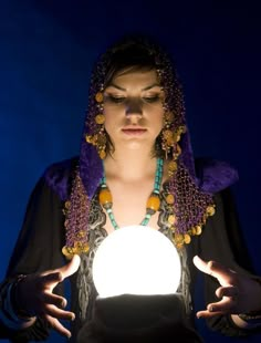 a woman holding a glowing ball in her hands and looking at the camera with an evil look on her face