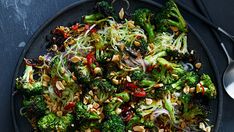 broccoli and other vegetables on a black plate with spoons next to it