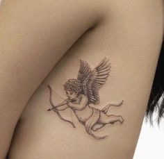 a tattoo on the side of a woman's thigh shows an angel with a bow and arrow