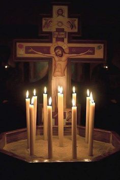 candles are lit in front of a crucifix