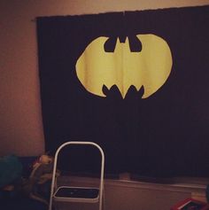 a batman silhouette on a black wall hanging in a child's room with a chair