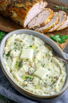 a bowl filled with mashed potatoes and meat on top of a wooden cutting board