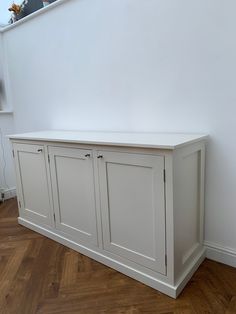 a white cabinet sitting on top of a hard wood floor