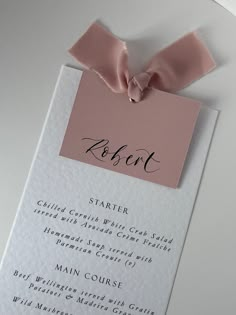 a pink and white menu card with a bow on the top that reads robert starker