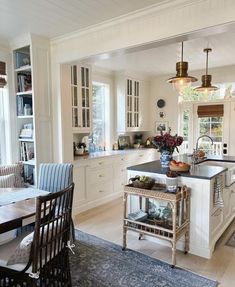 a kitchen filled with lots of white cabinets and counter top space next to a dining room table