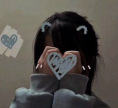 a woman covering her face with two hearts drawn on the back of her head and hands