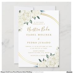 a wedding card with white flowers and gold foil on the bottom, in front of a marble