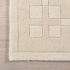 a white rug with squares on it and a wooden floor in the background, top view