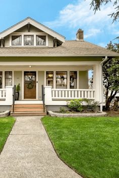 a white house with two front porches and green grass on the lawn in front of it