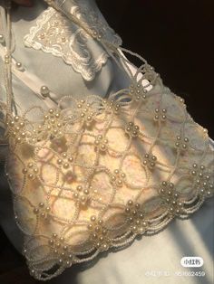 a close up of a white purse on a woman's chest with pearls and lace