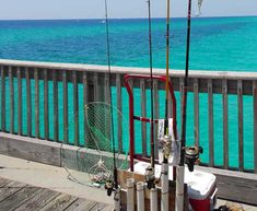 some fishing rods are sitting on a deck by the water