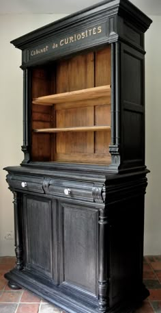 an old fashioned black cabinet with wooden shelves