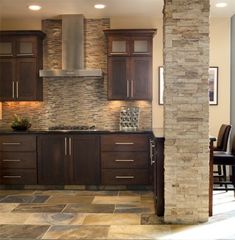 a kitchen with wooden cabinets and tile flooring next to a dining room table in front of a fireplace