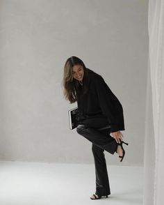 a woman in black is posing for the camera with her legs spread out and shoes on