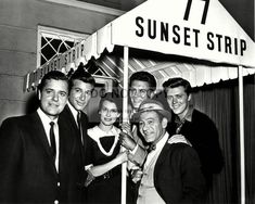 black and white photograph of men and women posing under a sign that says sunset strip