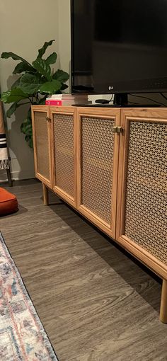 a flat screen tv sitting on top of a wooden cabinet next to a chair and rug