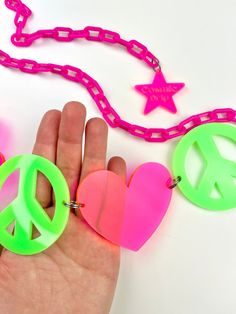 Spread the peace and love at your next festival! Made with bright vibrant colors that is sure to make you outfit pop. Our peace and love waist chain is handmade with high quality materials and will last you many festival seasons. - Chain is adjustable up to 40" (fits US size XXS-XL) - The chain is lightweight acrylic - Hearts are made with semi transparent material - UV reactive - "Cosmic Drip" charm at end of chain Festival Belt, Waist Chain, Green And Pink, The Peace, Semi Transparent, Green And Purple, Festival Season, Peace And Love, Pink And Green