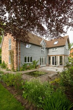 a large gray house sitting next to a lush green field